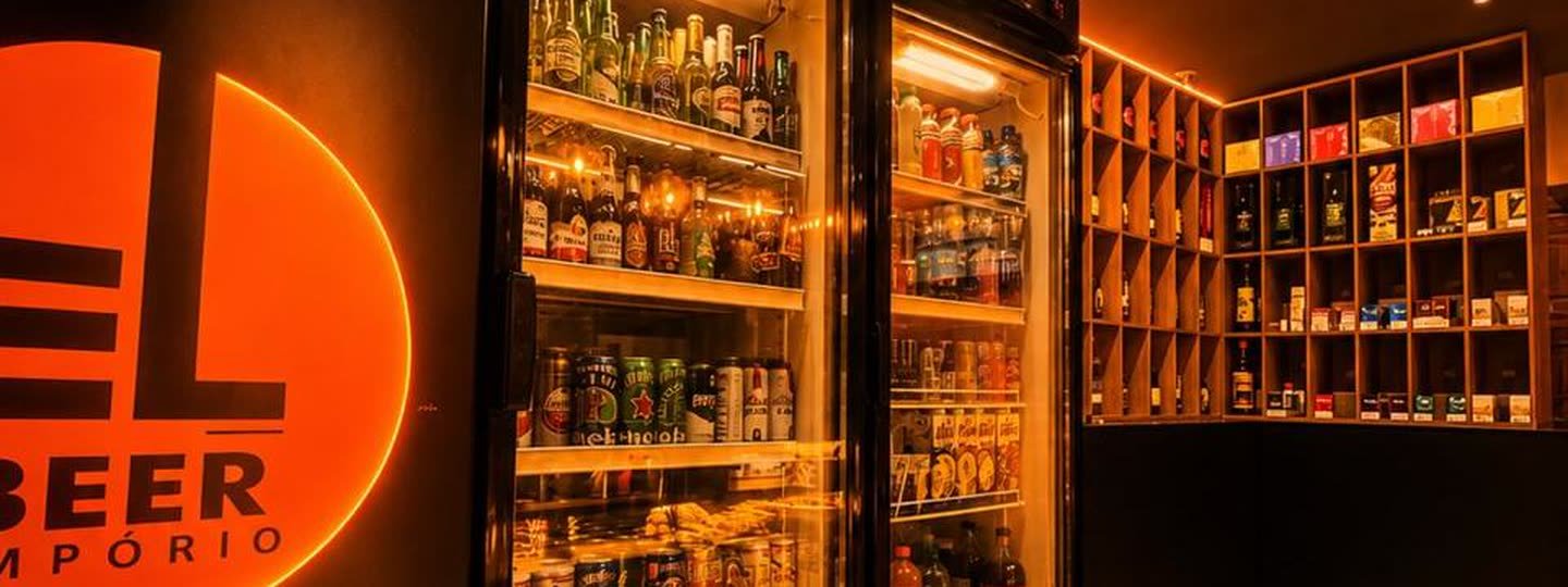 Freezers do El Beer cheios de cerveja em lata e garrafa, com o letreiro laranja aceso ao lado